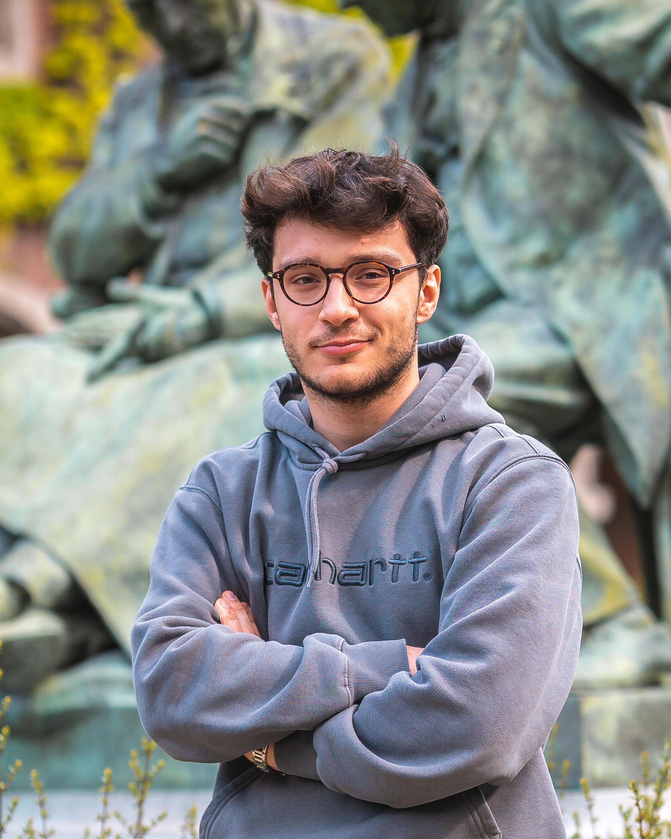 Mathieu Zilli, fondateur de ZILMA Studio, bras croisés, souriant, devant une statue en bronze.